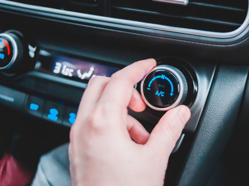 Hand adjusting a car's air-conditioning temperature dial