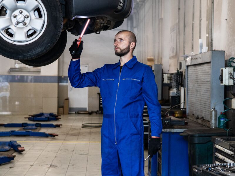 Mechanic working beneath a car raised on a two-post lift