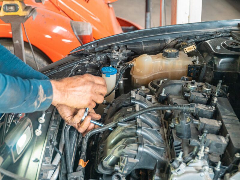 Hands repairing components in an open engine bay
